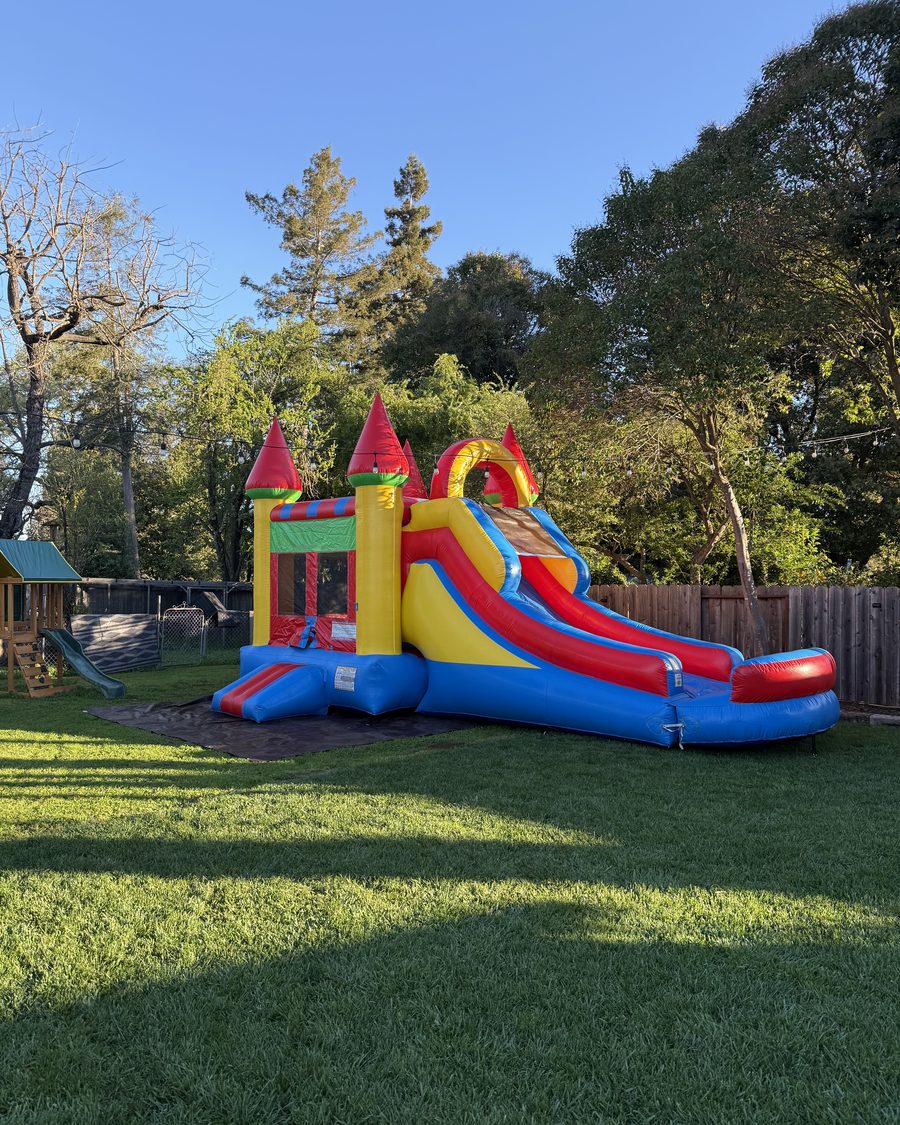 Napa Valley Jumpers castle bounce house with an attached slide, set up on grass in a Napa backyard at golden hour